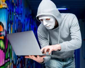 Hacker Mann mit weißer Maske und Laptop